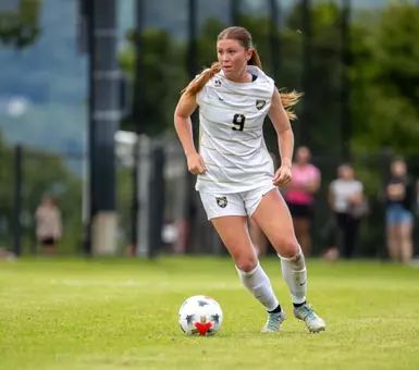 Sophia Henry dribbles ball up the field against Vermont
