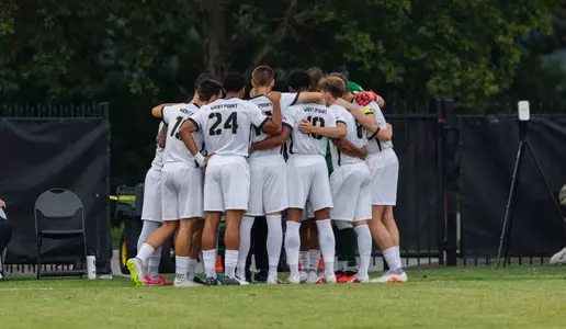 Men's soccer team huddles on the field before a game