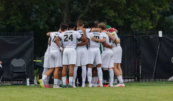 Men's soccer team huddles on the field before a game