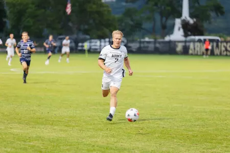 Riley Cullum kicks soccer ball during game against Yale