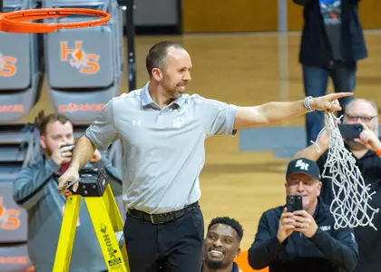 Head coach Chris Mudge smiles after cutting down the net at Johnson Coliseum