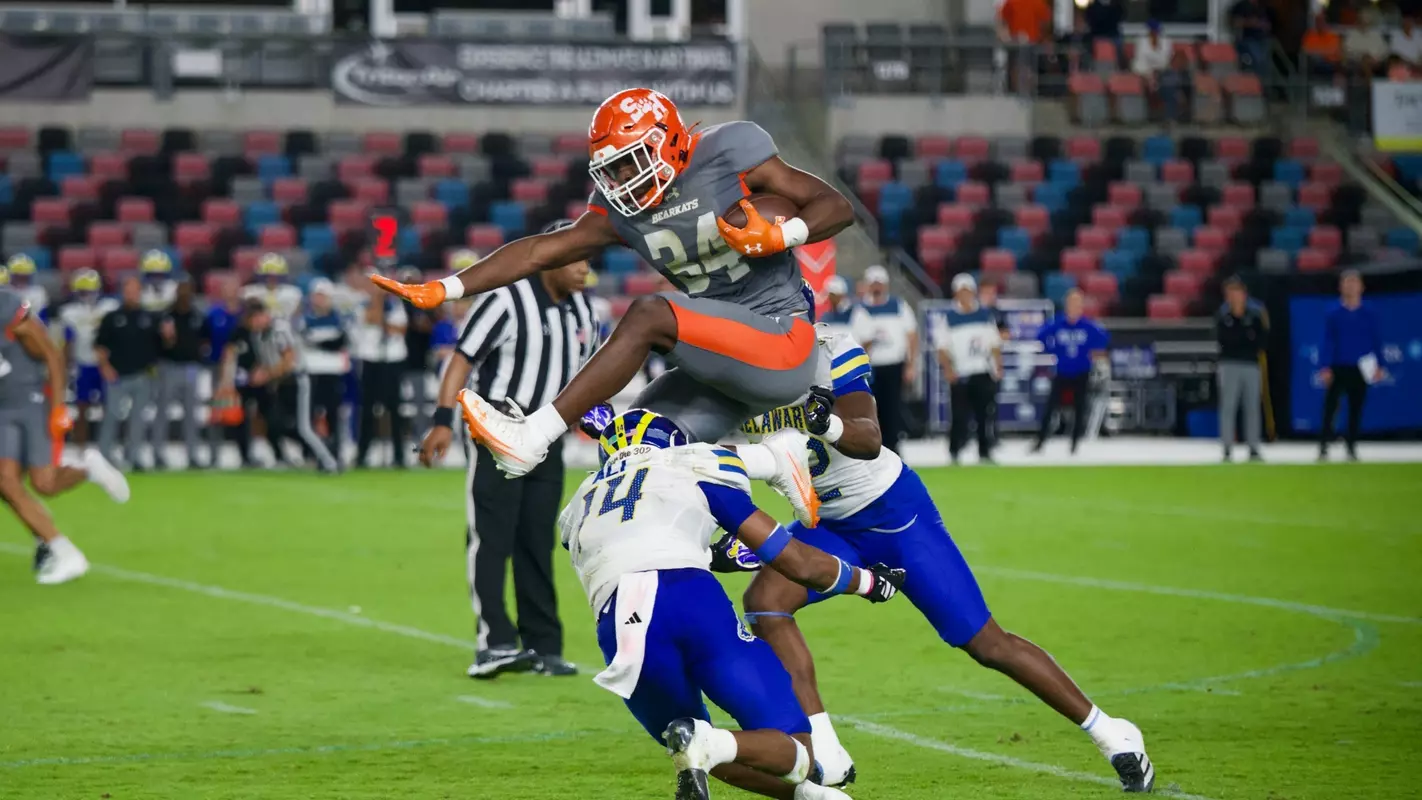 Running back Coco Brown hurdles a pair of defenders on his way to a 62-yard touchdown run