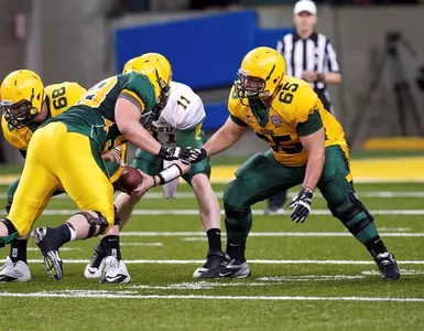 Adam Schueller (65) and the offensive line run a play