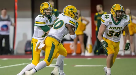 Lance Dunn takes a handoff from Easton Stick as Brock Robbins blocks