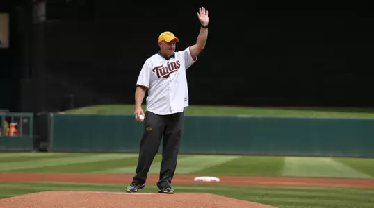 Chris Klieman in a Twins jersey waves to the crowd from the pitching mound