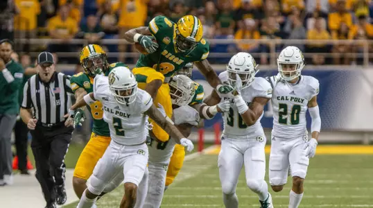 Bruce Anderson leaps over tacklers from Cal Poly