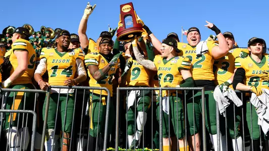 NDSU football players raise the 2019 NCAA championship trophy.