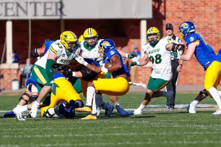 NDSU's Eli Mostaert, Costner Ching and Brayden Thomas close in to make a tackle