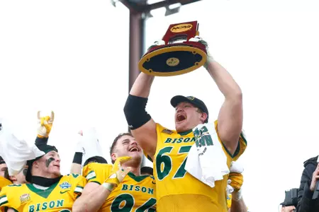 Cordell Volson raises the NCAA football national championship trophy