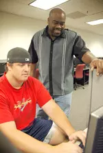 Pictured here with football player Kyle Young in the Ricchiuti Academic Center, Eric Sanders (right) influences student-athletes' experiences at Fresno State by advising and offering academic support.
