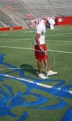 Fresno State's Alex Cordova paints the Bulldog logo at midfield on Thursday. The Dogs open the 2009 season on Saturday night against UC Davis.