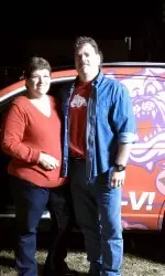 Loyal Bulldog fans, Darlene Franks and her husband, standing in front of their new Big Red Ride.