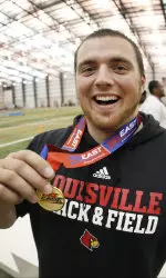 Sam Bombaugh holding one of his conference medals after one of his two indoor throwing titles.