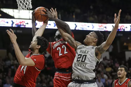 Wake Forest's John Collins (20) competes against Louisville's Deng Adel (22) and Anas Mahmoud (14) for a rebound during the first half of an NCAA college basketball game in Winston-Salem, N.C., Wednesday, March 1, 2017. (AP Photo/Chuck Burton)