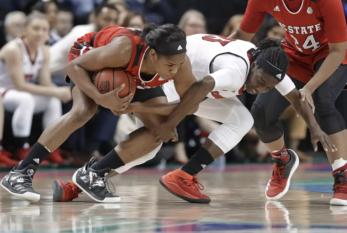 North Carolina State's Kiara Leslie, left, holds onto the ball as Louisville's Jazmine Jones, right, defends during the first half of a Women's Atlantic Coast Conference basketball tournament semifinal game in Greensboro, N.C., Saturday, March 3, 2018. (AP Photo/Chuck Burton)