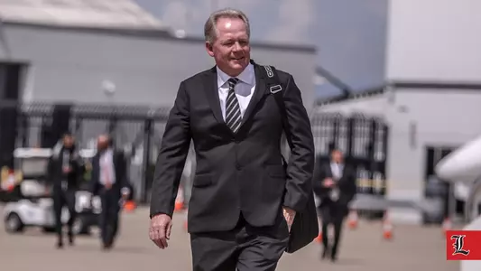 Football head coach Bobby Petrino walks to the airplane to Orlando.