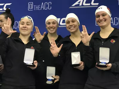 The 800 Free relay team poses with trophies on the podium