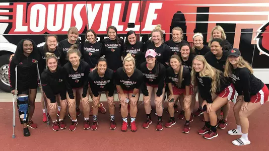 The softball team poses in front of the team bus