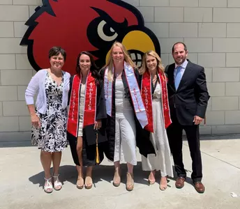 Field hockey seniors Katie Walsh, Ayeisha McFerran and Taylor Stone pose with head coach Justine Sowry and associate head coach Lucas Piccioli after graduation