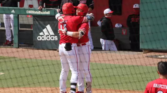 Alex Binelas and Lucas Dunn hug at home plate after a home run at NC State.