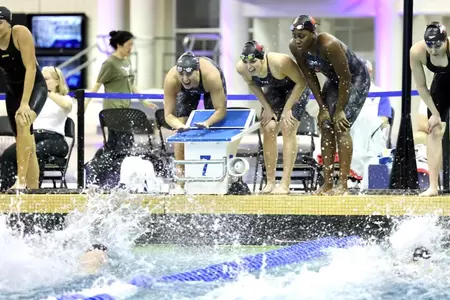 The 200 free relay team watches the finish of the race