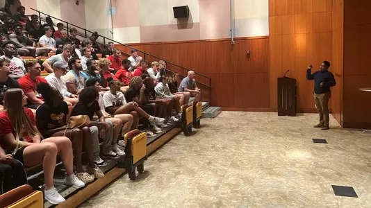 Football and women's basketball players in the auditorium at the Ali Center