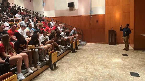 Football and women's basketball players in the auditorium at the Ali Center