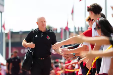 Jeff Brohm high fives fans during Card March before the game against Georgia Tech at L&N Stadium on September 21, 2024.