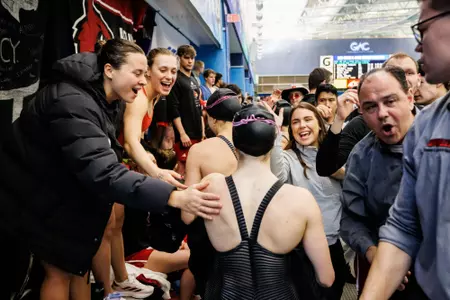 Women's swimming celebrate on deck after medalling in relay