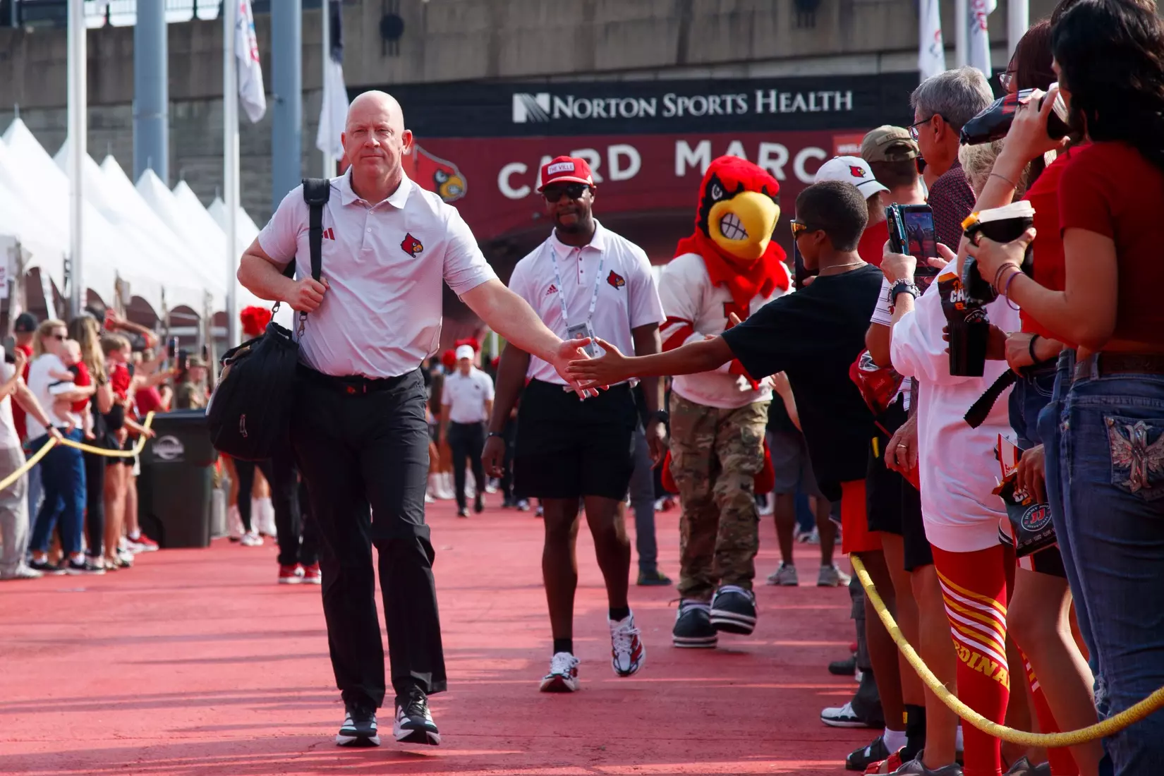Jeff Brohm high-fives a fan during the Card March before the game against Villanova at L&N Stadium on September 11.
