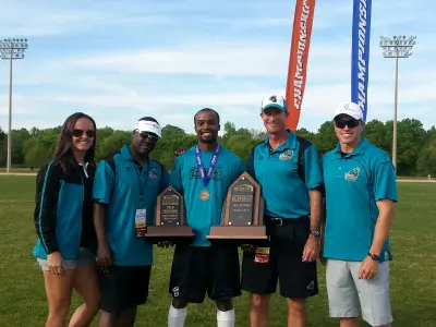 Reggie Nelson holding his Field Performer of the Year trophy and Big South Conference Runner-Up trophy