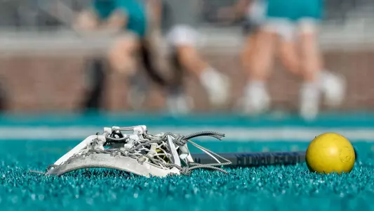 Lacrosse stick and ball on turf