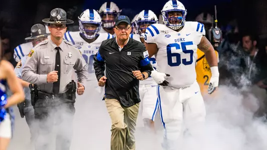Head coach David Cutcliffe runs out with the Blue Devils prior to their game with Alabama