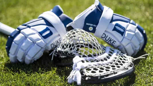 Duke men's lacrosse gloves and stick lay on the ground