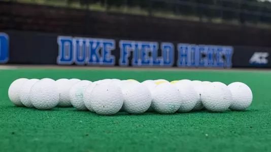 A pile of field hockey balls on the ground at Williams Field at Jack Katz Stadium