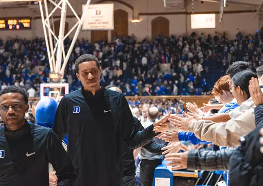 Justin Robinson high fives fans during a game in Cameron Indoor Stadium