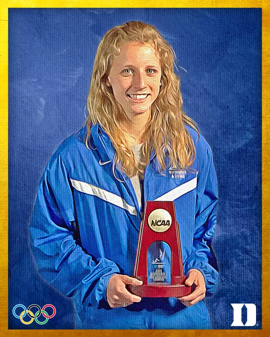 Hall of Fame portrait of Abby Johnston McGrath, a former Duke diver, smiling while holding an NCAA trophy. She is wearing a blue jacket with 'Duke Swimming & Diving' visible on the chest. The image has a blue textured background with a yellow border, Olympic rings in the lower left corner, and a Duke 'D' logo in the lower right corner.