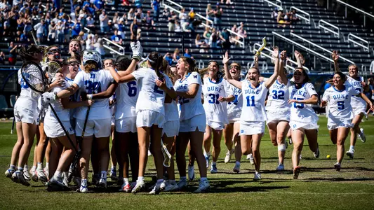 Duke women's lacrosse team runs on the field to celebrate a victory in Koskinen Stadium.