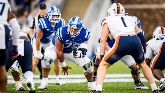 Duke center Matt Craycraft, in a blue helmet, blue jersey and white pants, snaps the ball against No. 20 Virginia on November 15, 2025, at Brooks Field at Wallace Wade Stadium.