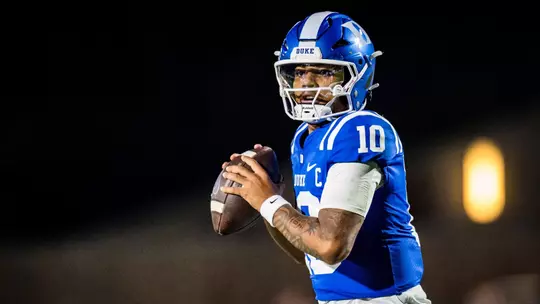 Duke quarterback Darian Mensah, in a blue helmet, blue jersey and white pants, drops back to throw a pass against No. 20 Virginia on November 15, 2025, at Brooks Field at Wallace Wade Stadium.