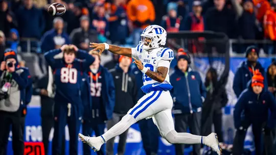 Duke quarterback Darian Mensah, wearing a white helmet, white jersey and white pants, makes an acrobatic throw on the run versus No. 16 Virginia in the 2025 ACC Championship Game.