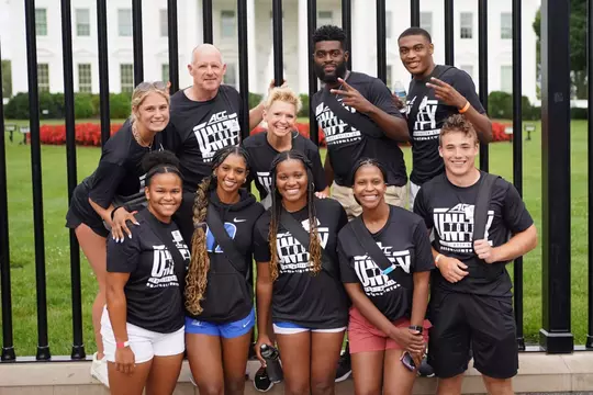 Charlie Johnson and Duke student-athlete pose for a group photo wearing ACC Unity Tour shirts in front of the White House.