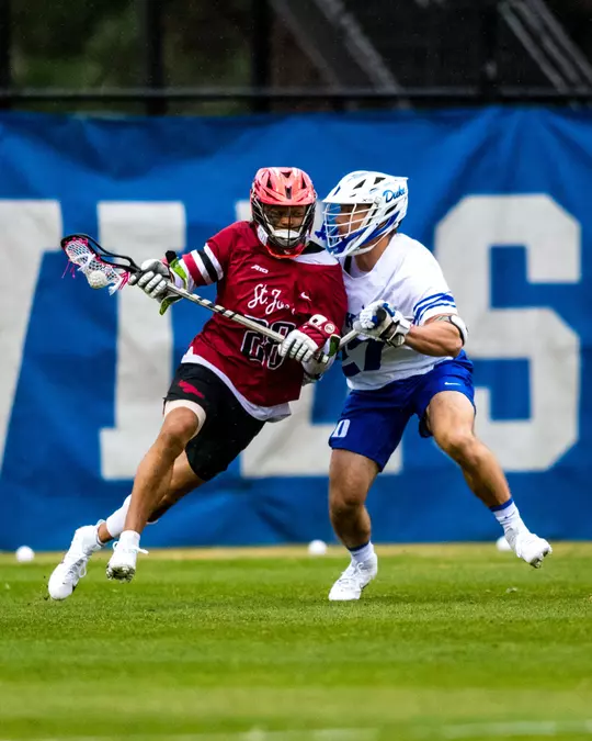 Duke men's lacrosse's Charlie Johnson plays defense against a St. Joseph's player during a game.