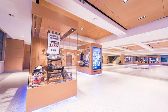 Glass display case featuring memorabilia from Duke’s 2015 men’s basketball national championship with the Rubenstein Pavilion's illuminated exhibits in the background.
