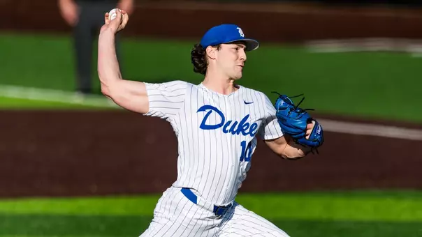 Duke baseball pitcher Aidan Weaver, wearing a white jersey with blue pinstripes, holds the ball above his head while making a pitch.