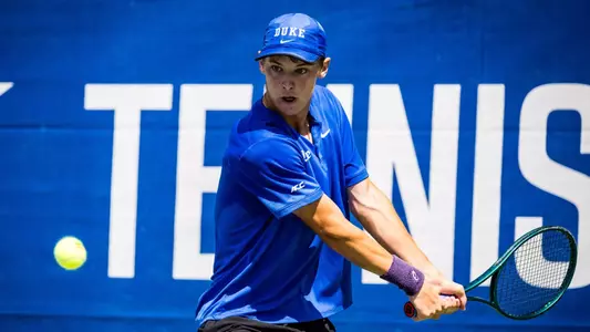 Duke's Cooper Williams, wearing a blue shirt and blue hat, lines up a backhand shot during Duke's quarterfinal ACC Championship match against Wake Forest at the Cary Tennis Park on April 17, 2026.
