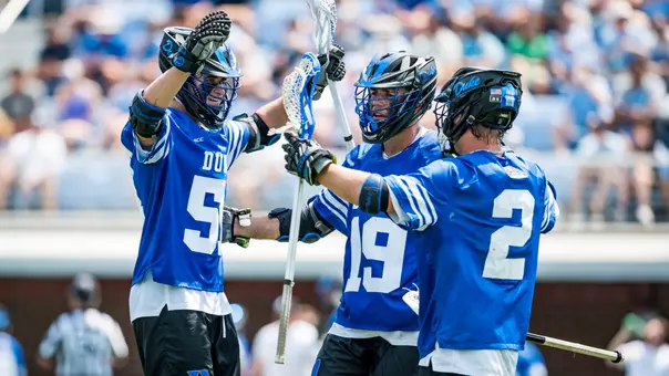 Four Duke men's lacrosse players celebrate a goal against North Carolina