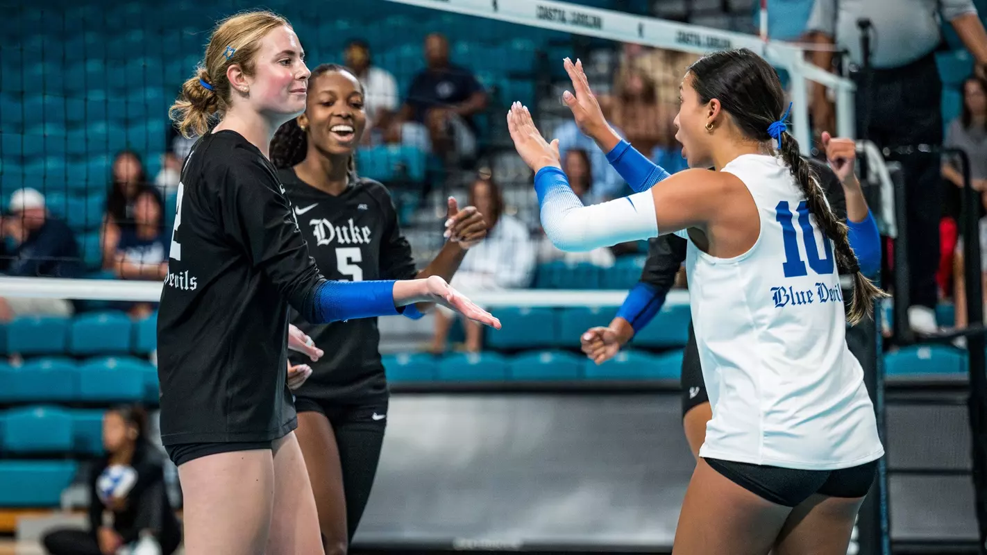 Duke volleyball coach discussing strategy with team during a game