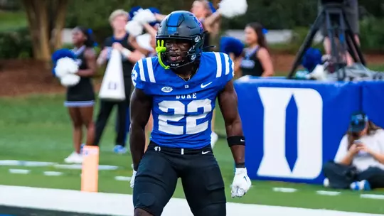 Duke running back Jayvian Tanelus, wearing a black helmet, blue jersey and black pants, yells in celebration in the end zone after scoring his first career touchdown during Duke's 35-7 victory against Stanford on September 19, 2026.