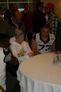Ed Wesley and Spencer Thompson visit with a child at Make-A-Wish Night.
